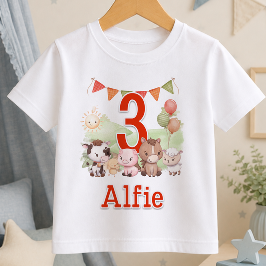 A white t-shirt with a cartoon image of farm animals and the number 3, along with the name "Alfie" printed on it.
