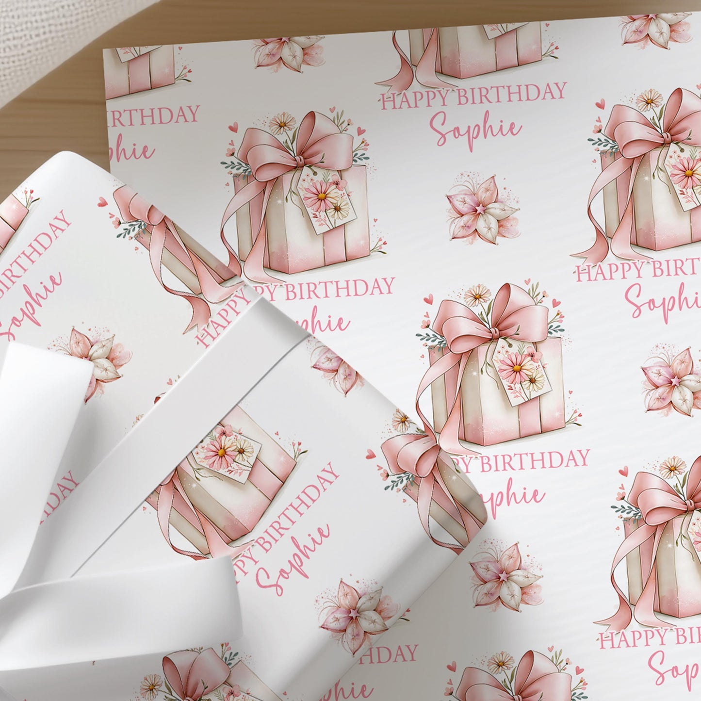 Personalised pink floral wrapping paper sheet laid flat showing the full repeating gift box and flower pattern with custom name and age.