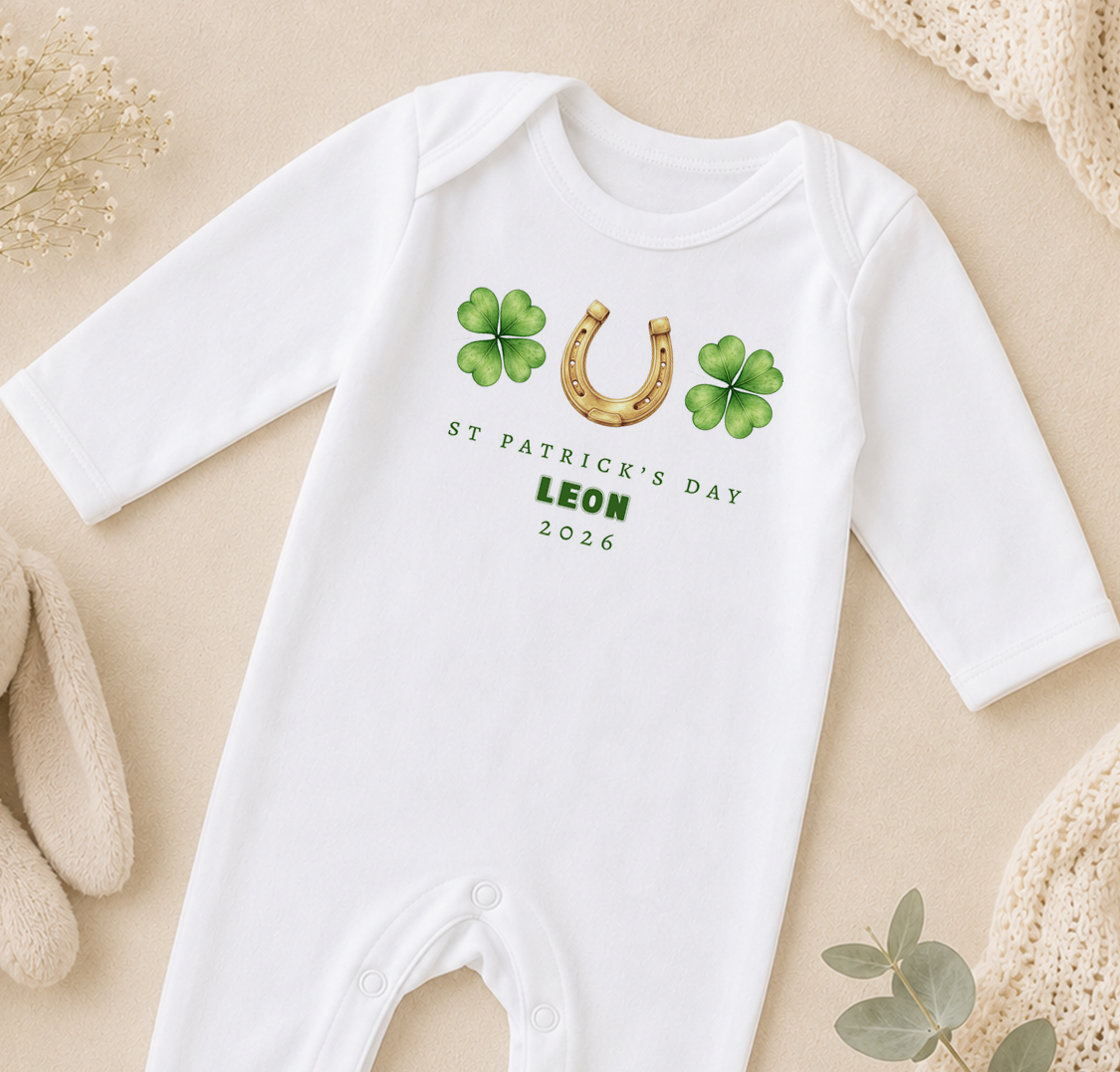 A white onesie with St. Patrick's Day and a horseshoe design, along with the text "ST PATRICK'S DAY LEON 2026" printed on it.