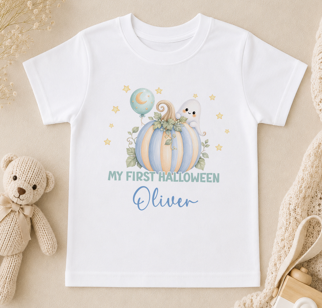 A white t-shirt with a Halloween-themed graphic design, including a pumpkin, ghost, and stars, along with the text "My first Halloween Oliver".