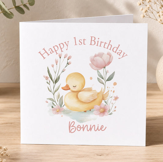 Personalised duck theme first birthday card with custom name and age printed on the front, surrounded by flowers and greenery
