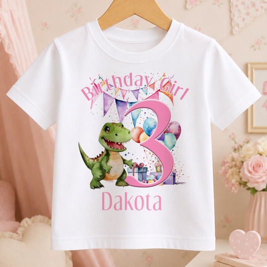 A white t-shirt with a dinosaur and birthday decorations, specifically a 3-year-old girl's birthday shirt.