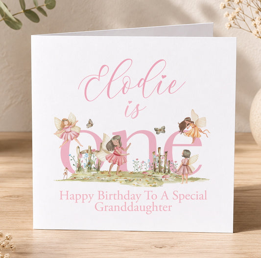 Personalised first birthday card featuring pink woodland fairies around a large number one, shown with a personalisation example for a granddaughter