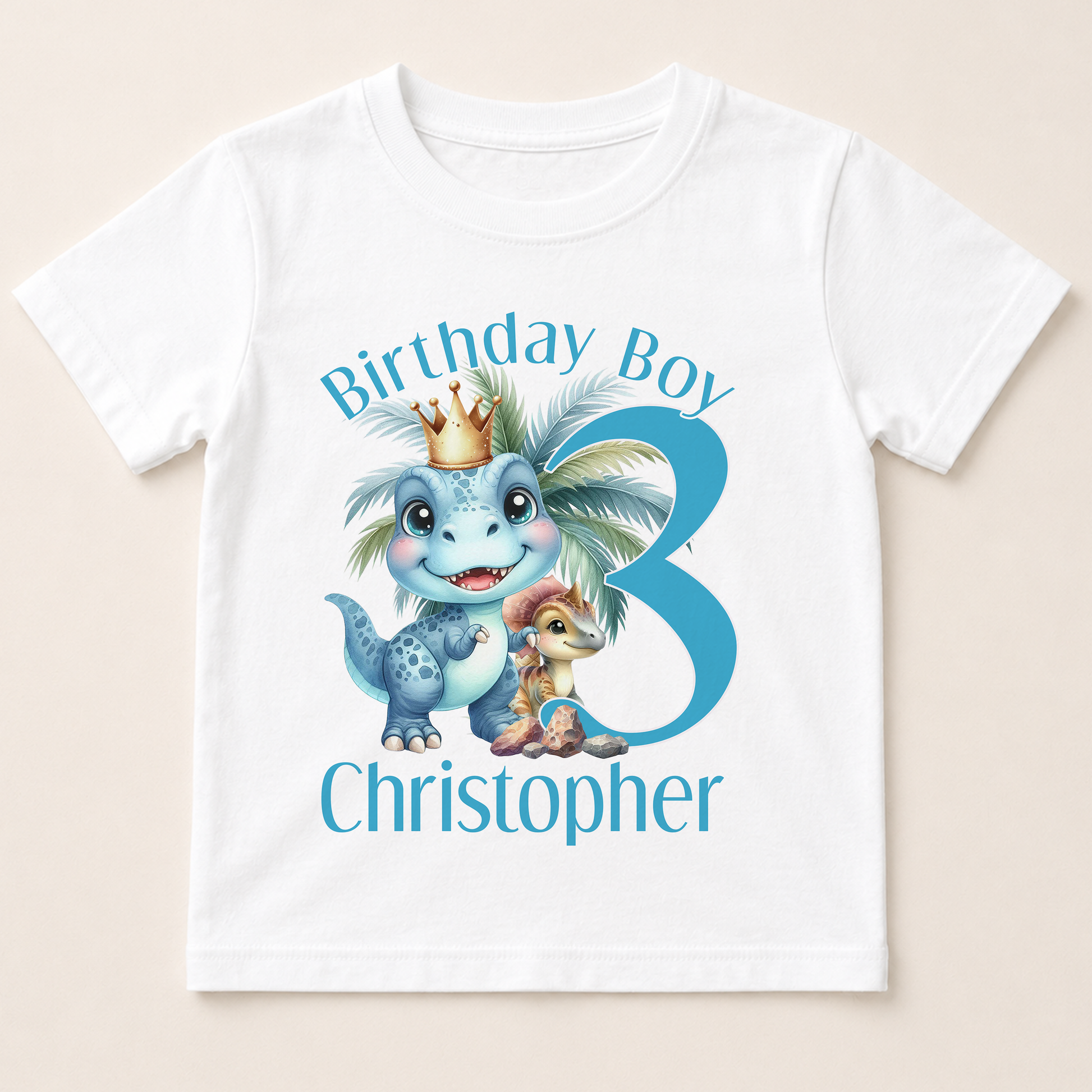A white t-shirt with a graphic design featuring a dinosaur wearing a crown and the text "Birthday Boy Christopher" along with a number 3.