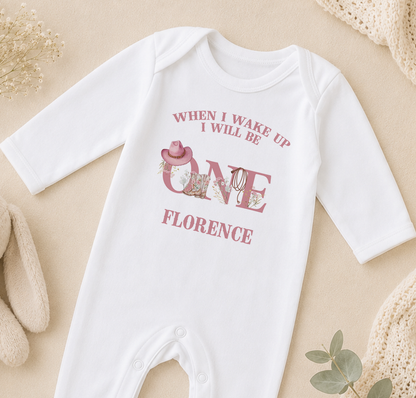 A white onesie with a pink cowboy hat and the text "WHEN I WAKE UP I WILL BE ONE FLORENCE" printed on it.