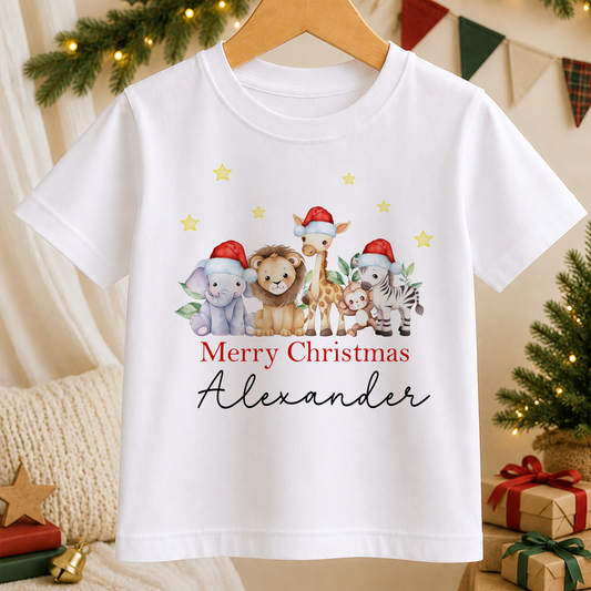 A white t-shirt with a Christmas-themed graphic design featuring a group of animals, including a lion, giraffe, and zebra, wearing Santa hats. The text "Merry Christmas Alexander" is written below the image.