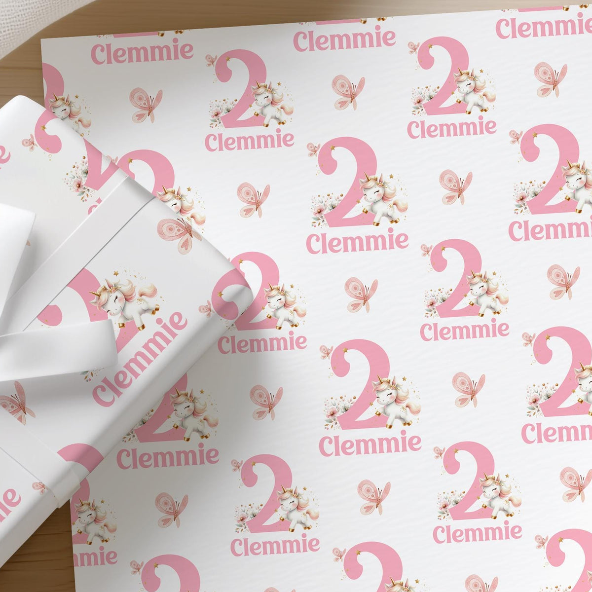 Roll of personalised pink unicorn wrapping paper with an example name and age printed on the design