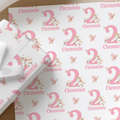 Roll of personalised pink unicorn wrapping paper with an example name and age printed on the design