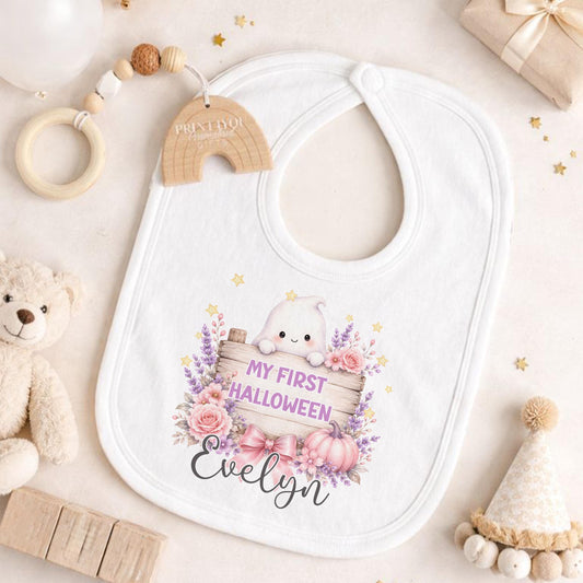 Personalised baby’s first Halloween white bib featuring a cute pastel ghost holding a wooden sign with pink flowers, pumpkin and baby’s name.