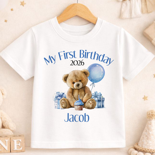 White personalised first birthday t-shirt printed with a teddy bear, blue balloon and 'My First Birthday' name design.