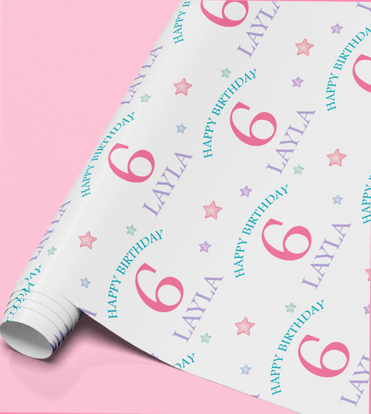 Roll of pastel stars wrapping paper printed with the number six and 'Happy Birthday Layla' as a sample design.