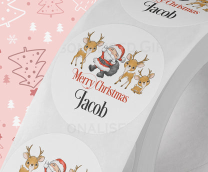 Personalised Santa and reindeer Christmas sticker on a strip of five, glossy white 5cm round gift label printed with a custom name