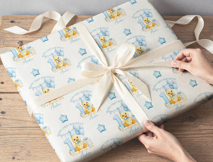 Personalised duckling wrapping paper wrapped around a gift with ribbon, featuring the custom name, blue number one and balloons.