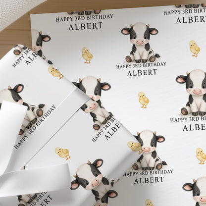 Personalised cow wrapping paper printed with a custom name and age, shown as a full sheet
