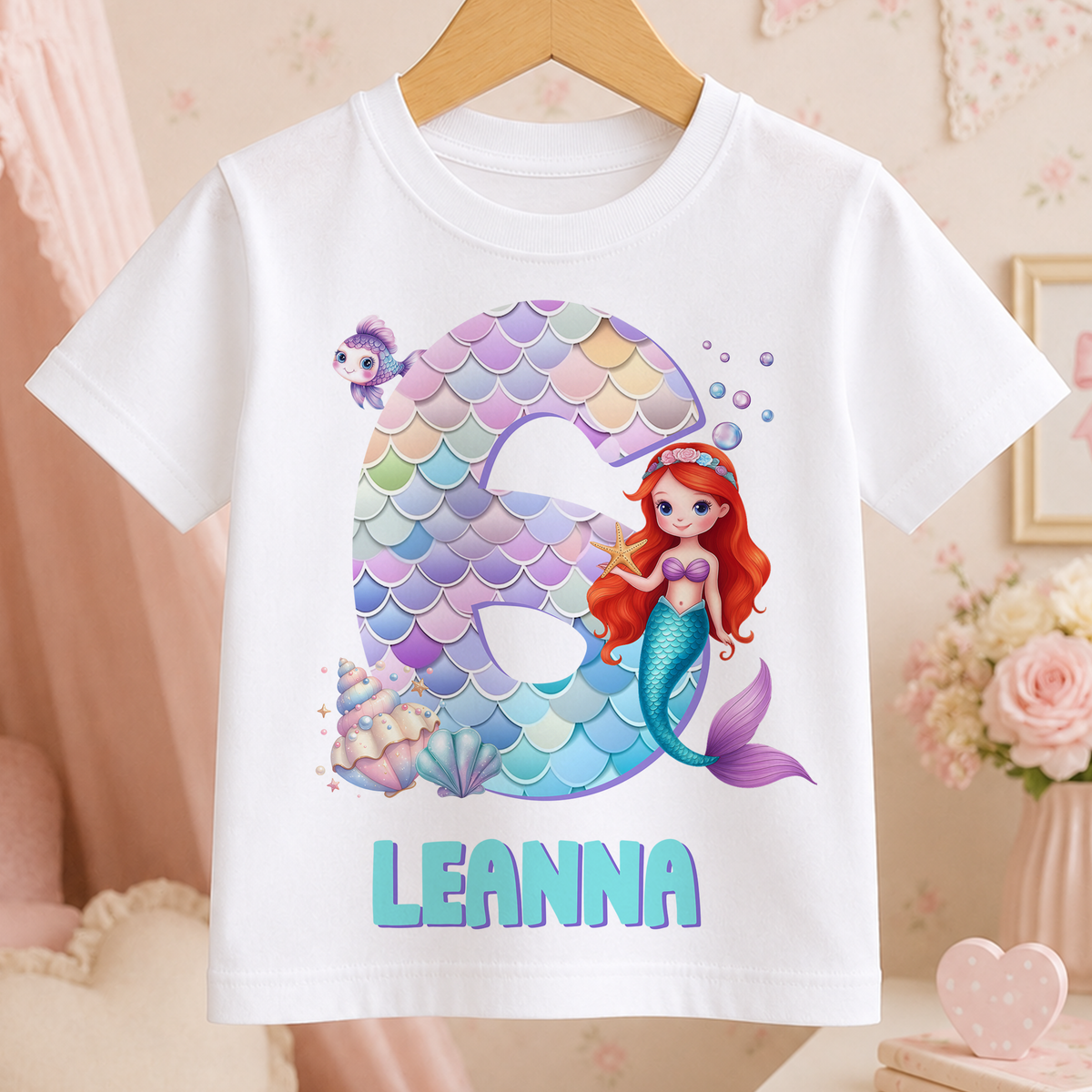 White cotton t-shirt personalised with a pastel mermaid design, a scaled birthday number and a custom name printed below.
