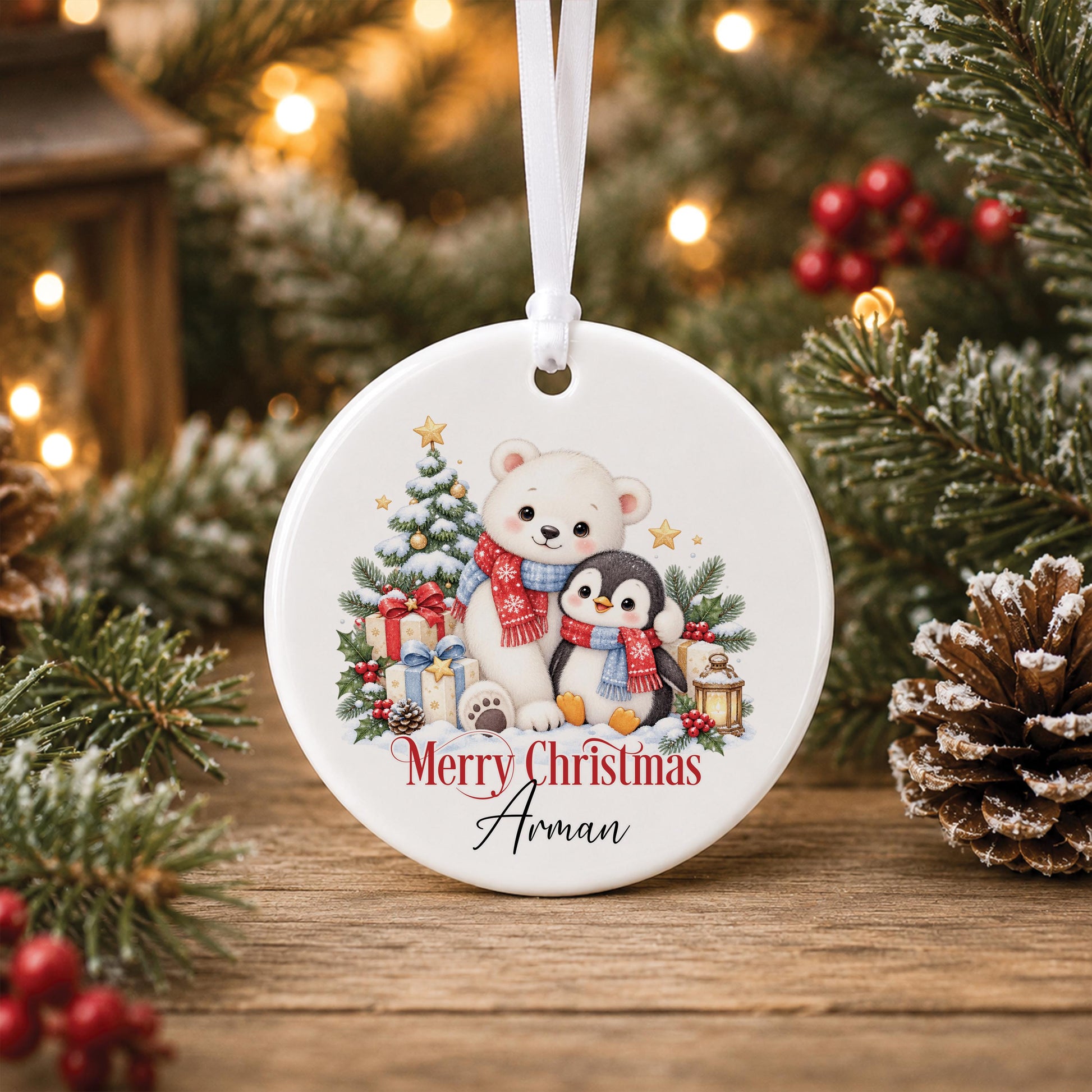 Personalised Christmas bauble, white ceramic ornament with a polar bear and penguin snowy design printed with a name, hanging on a Christmas tree