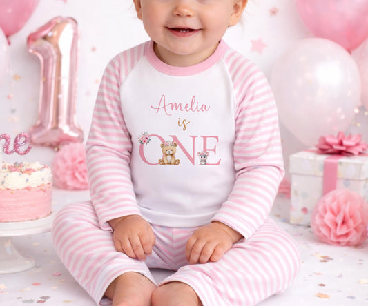 Personalised first birthday pyjamas with a floral teddy bear design and the baby's name printed on the front.