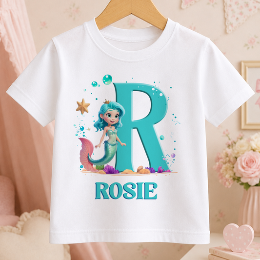 A white t-shirt with a large letter "R" and a mermaid character printed on it, along with the name "ROSIE" below the letter.