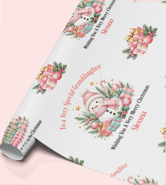 Rolled sheet of personalised pink snowman Christmas wrapping paper with a name and relation