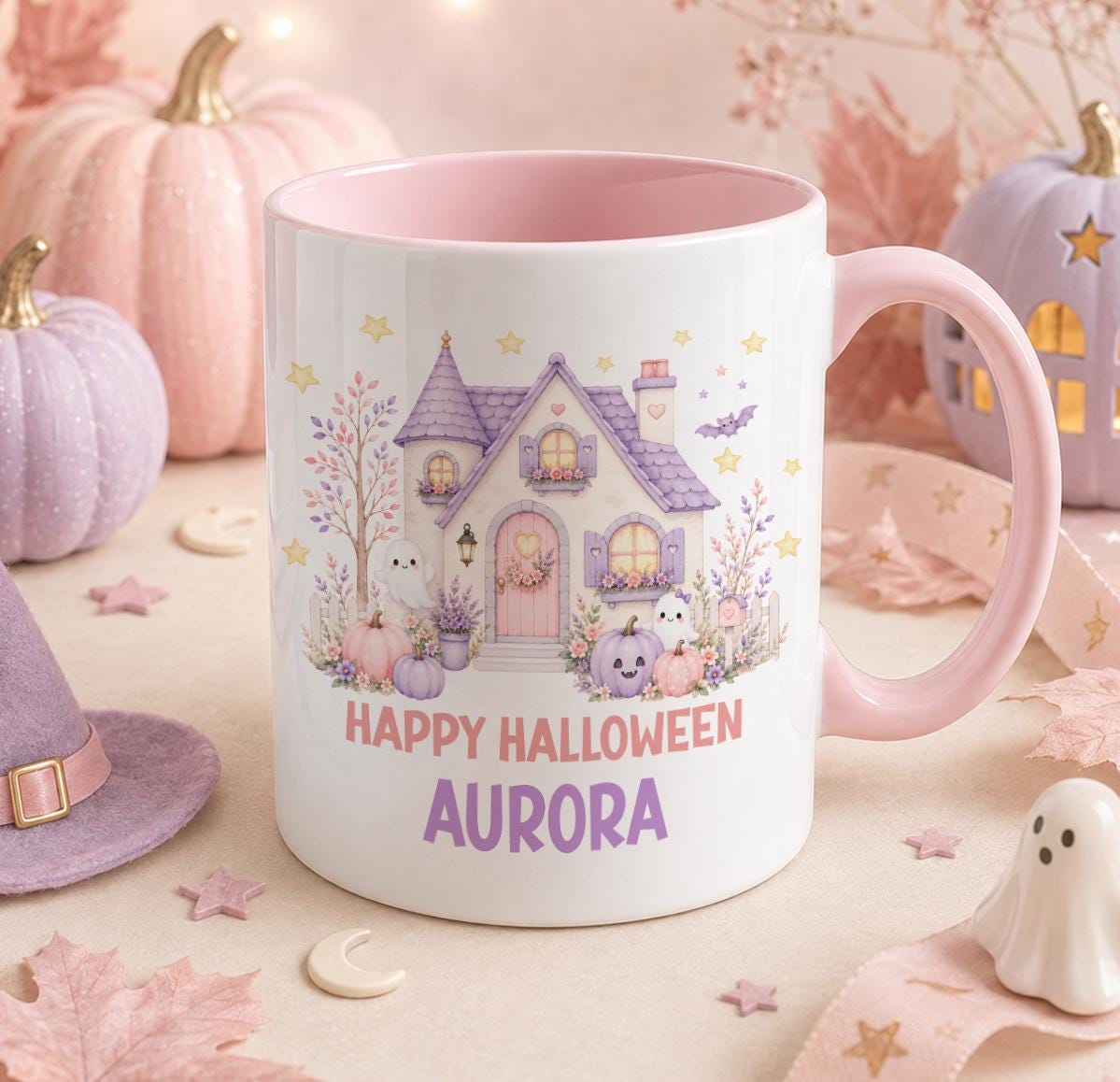 Personalised Halloween mug with a pink handle and inner, featuring a pastel purple haunted cottage with two cute ghosts and pumpkins, printed with Happy Halloween Aurora