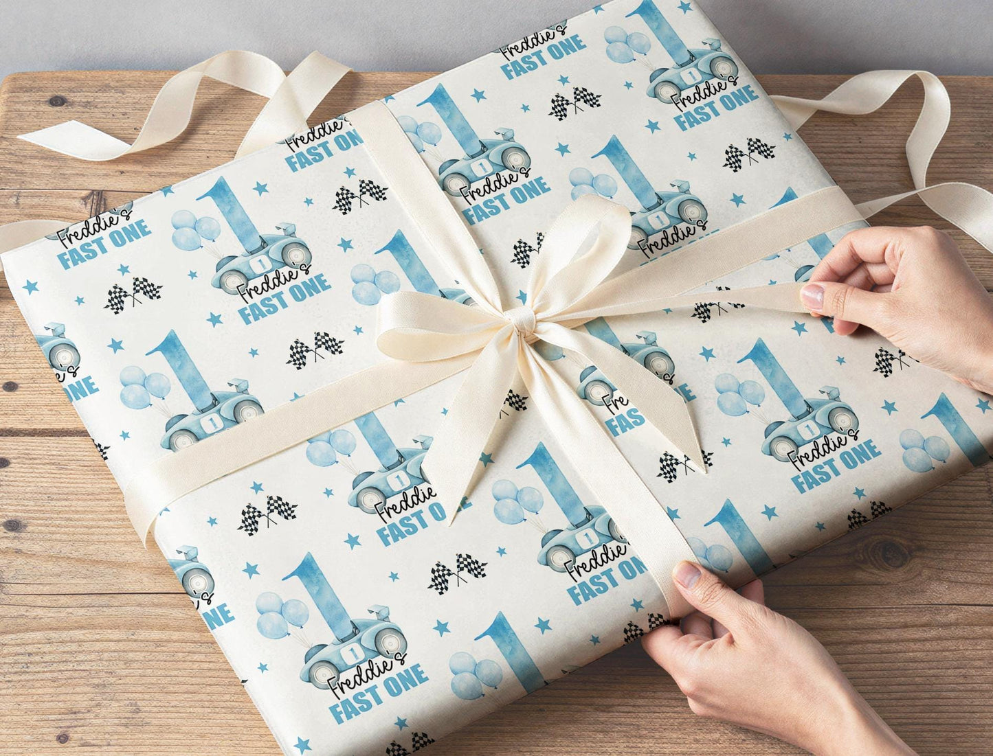 Close-up of hands wrapping a birthday present in the personalised blue racing car wrapping paper