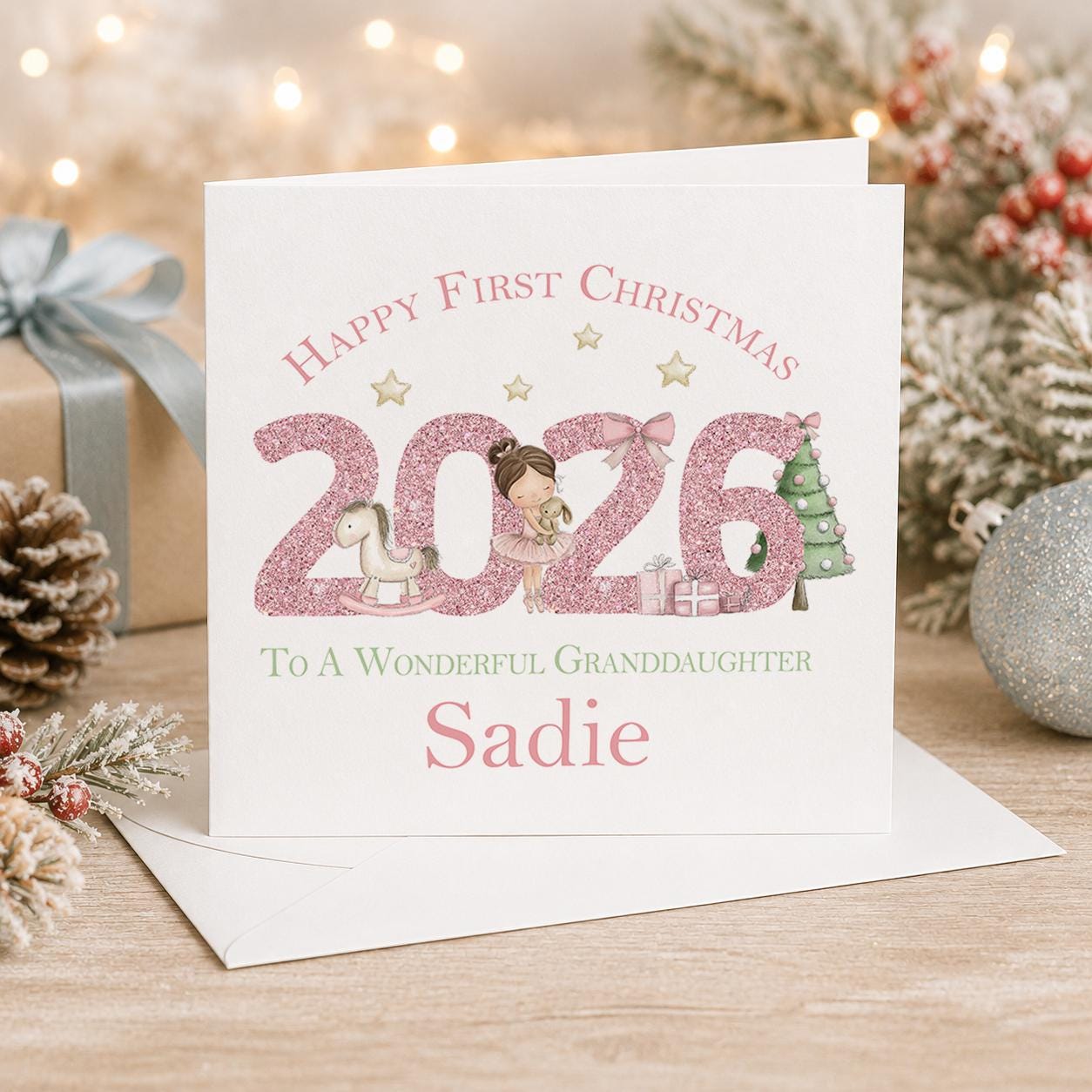 Personalised first Christmas card, white 6x6 inch square card printed with a large pink 2026, Happy First Christmas and a name