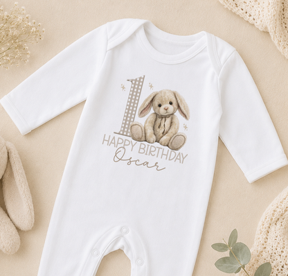 A white onesie with a bunny graphic and the text "Happy Birthday Oscar" printed on it, along with a number 1.
