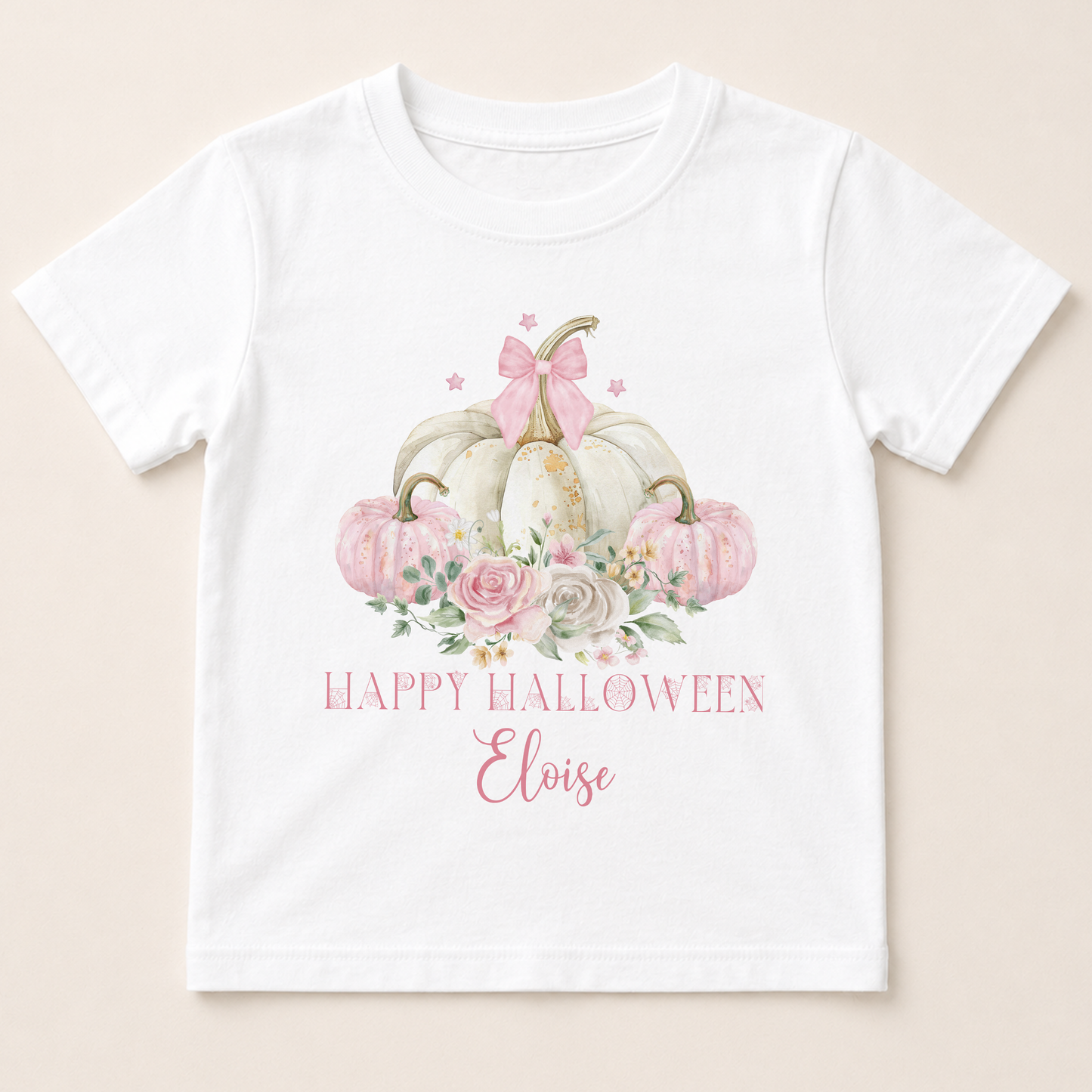 A white t-shirt with a graphic design featuring a floral arrangement of pumpkins and a bow, along with the text "Happy Halloween Eloise".