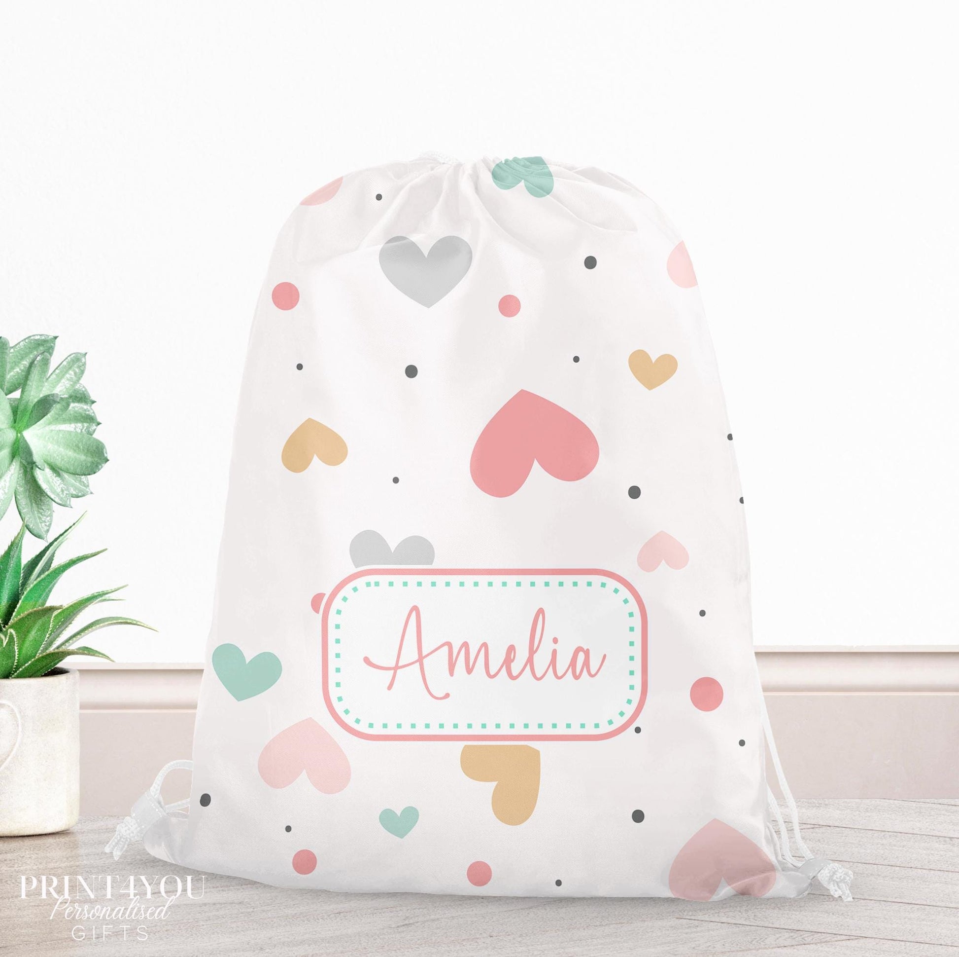 Personalised pastel heart print drawstring PE bag in pink, mint, mustard and grey, printed with a custom name on the front