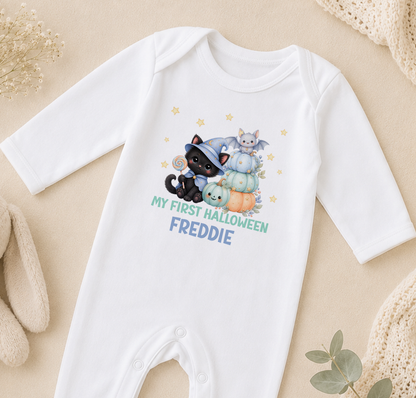 A white onesie with a Halloween-themed design, featuring a witch, a cat, and pumpkins, along with the text "My first Halloween Freddie".