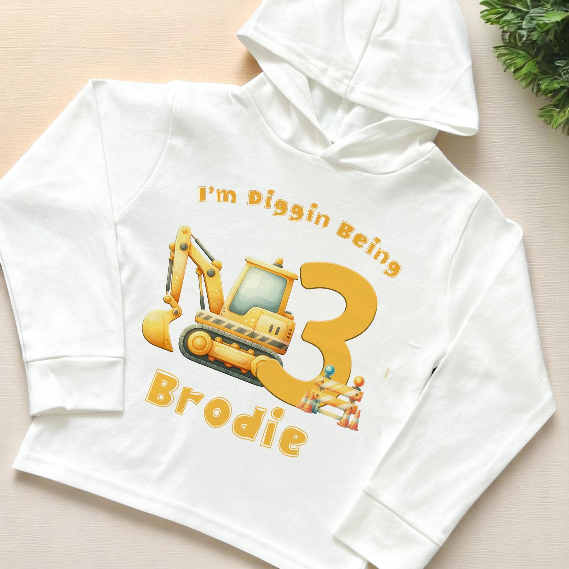 Birthday Digger personalised long-sleeved hooded t-shirt in white jersey cotton, 6-12 months size, front view showing digger birthday number design