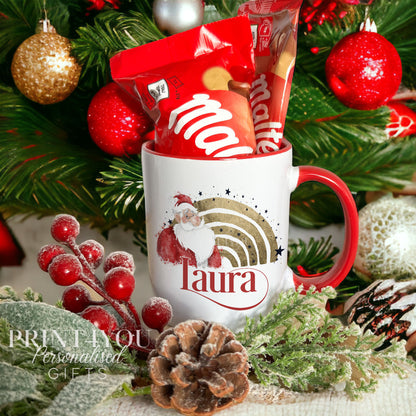 White ceramic Christmas mug with a red handle, personalised with a custom name and a gold foil rainbow Santa design