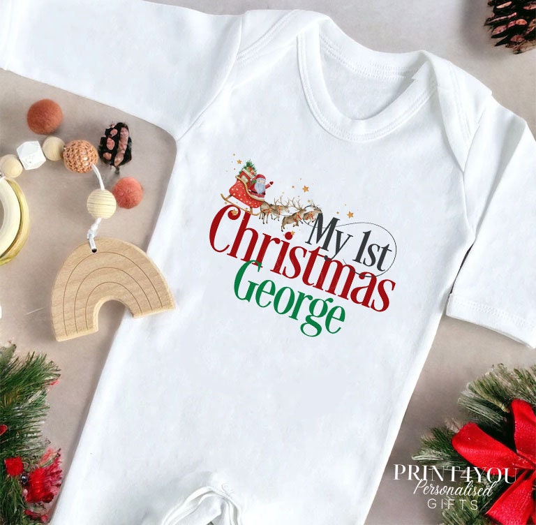 Close-up of the Santa sleigh print and personalised name on a baby's first Christmas vest