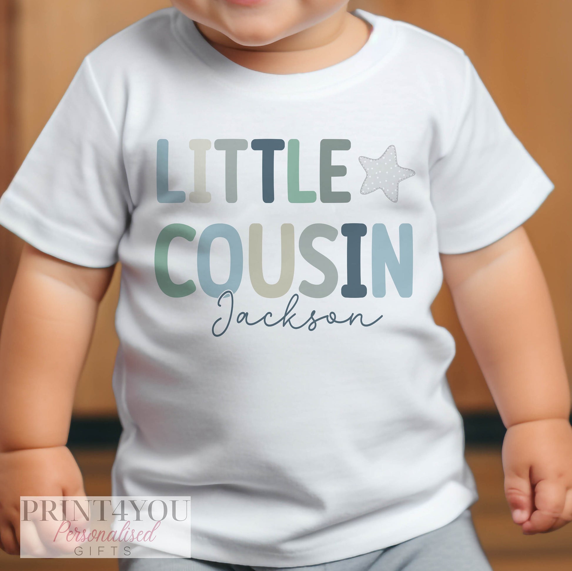 Close-up of the personalised little cousin print on soft cotton baby clothing.