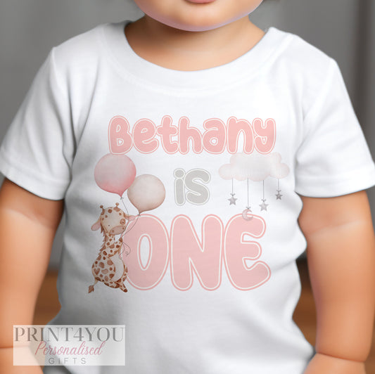 Personalised pink giraffe first birthday bib with the baby's name printed on the front.