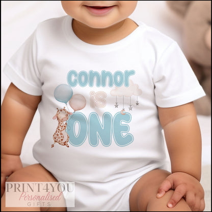 Personalised blue giraffe first birthday t-shirt with custom name printed on the front.