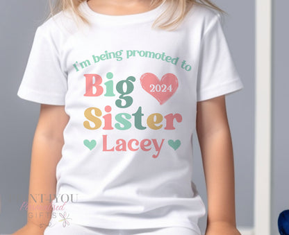 White cotton Promoted to Big Sister t-shirt with pastel heart design, shown in the 6-12 months size
