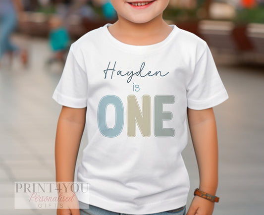 Pastel-coloured bib personalised with baby's name and 'I am One' for a first birthday.