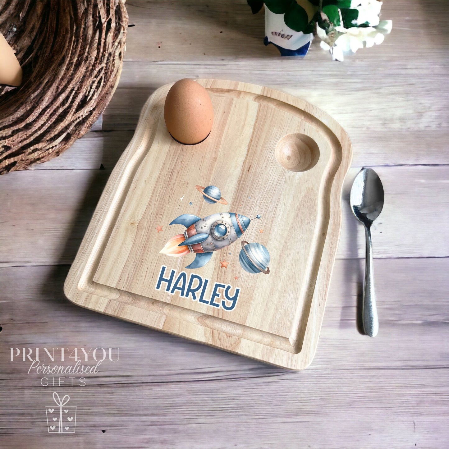 Wooden toast-shaped breakfast board with a rocket ship space design and personalised name, with two egg holes for boiled eggs and soldiers