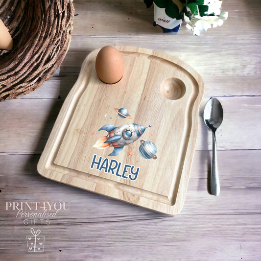 Wooden toast-shaped breakfast board with a rocket ship space design and personalised name, with two egg holes for boiled eggs and soldiers