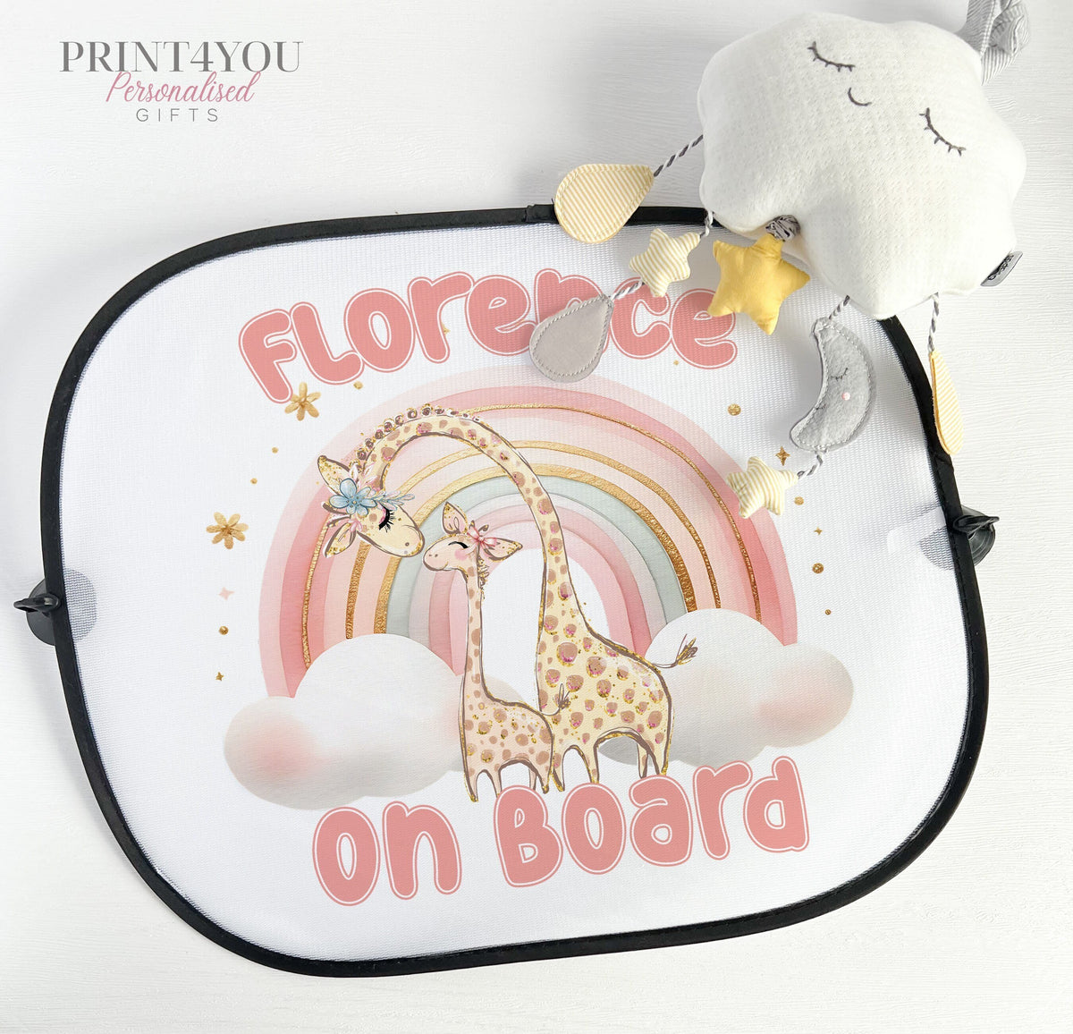 Pink giraffe and rainbow car sun shade with baby on board design, shown attached to a car window