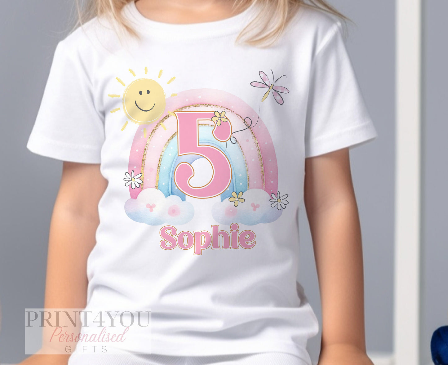 Personalised rainbow birthday t-shirt laid flat, showing the printed name and age.