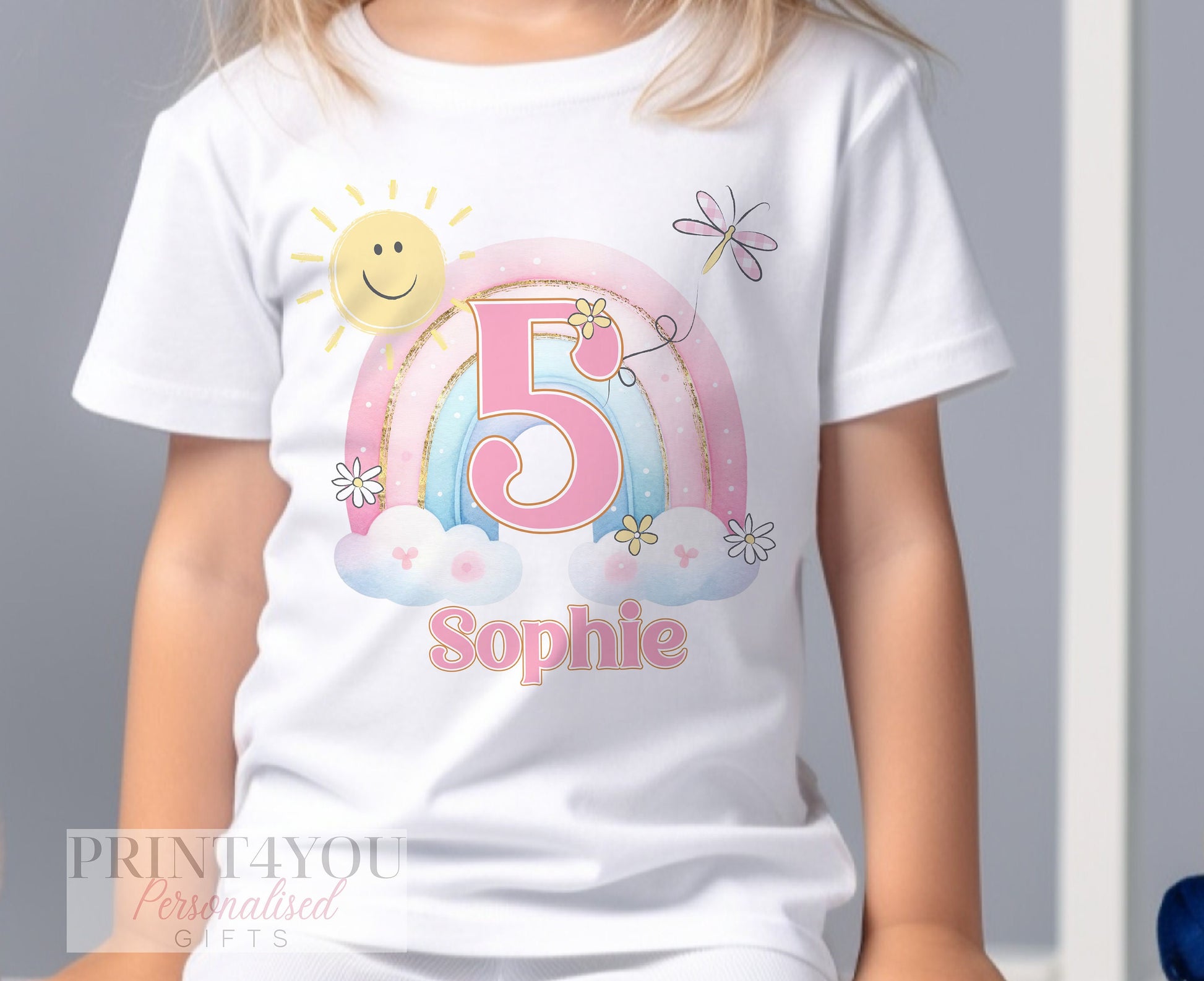 Personalised rainbow birthday t-shirt laid flat, showing the printed name and age.