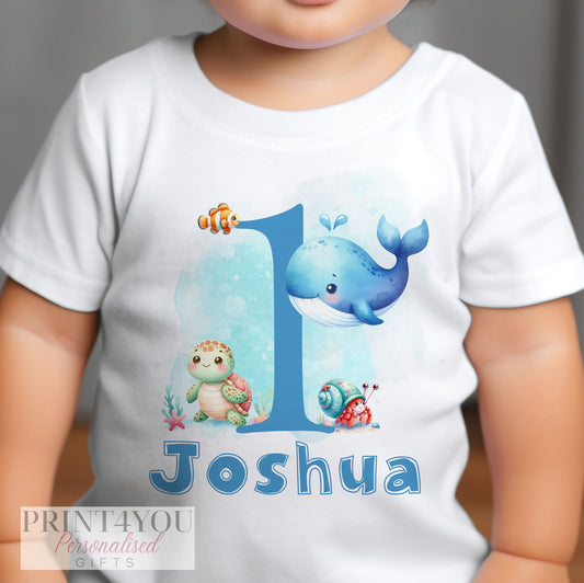 Personalised fish and whale first birthday bib, printed with a custom name in blue text.