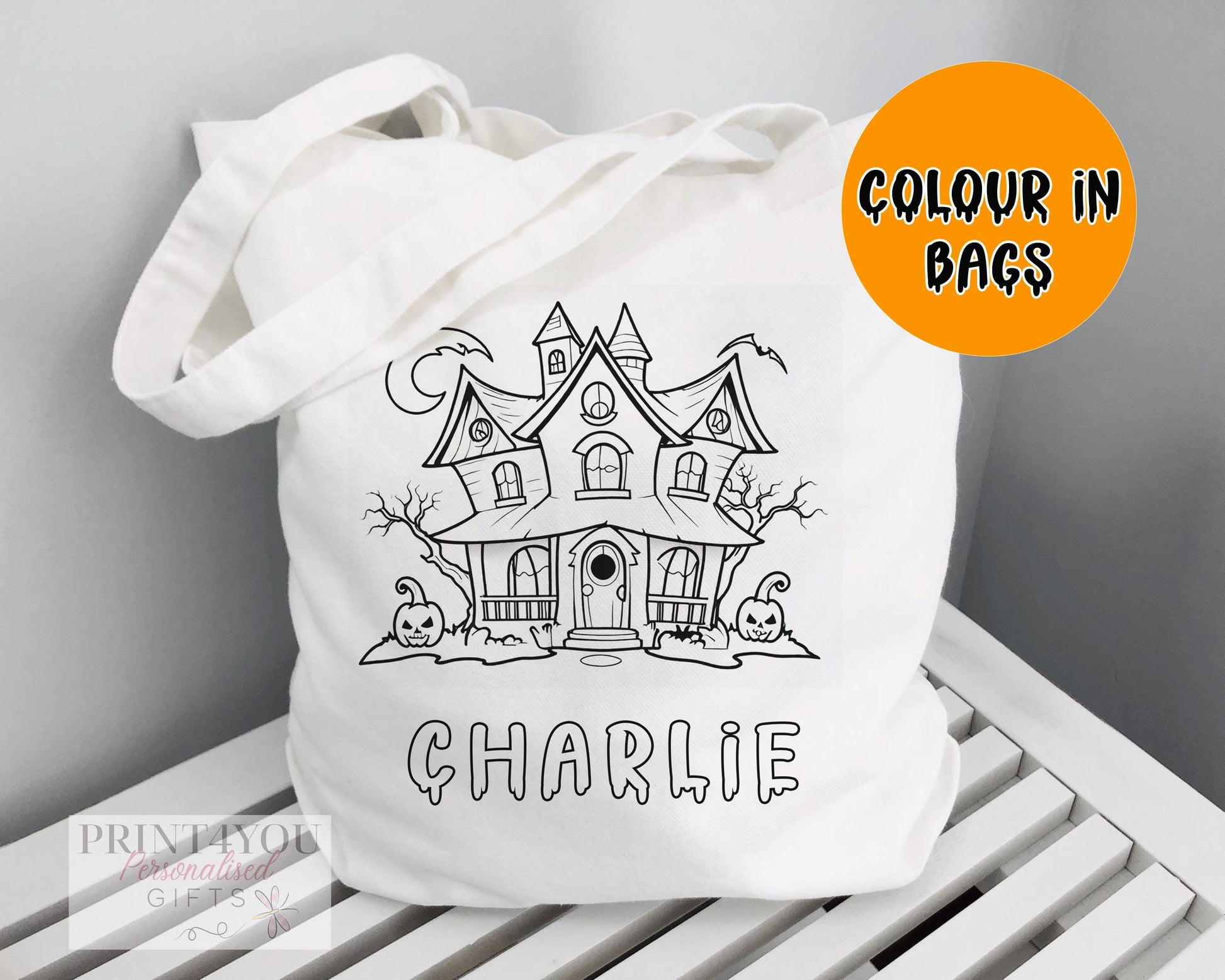 White cotton tote bag printed with a black-and-white haunted house outline, ready to colour in
