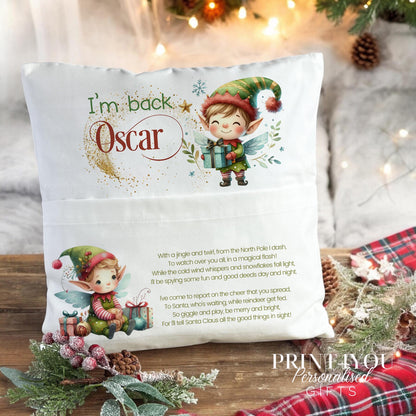 Personalised elf Christmas cushion styled on a bed with a toy elf peeking from the front pocket