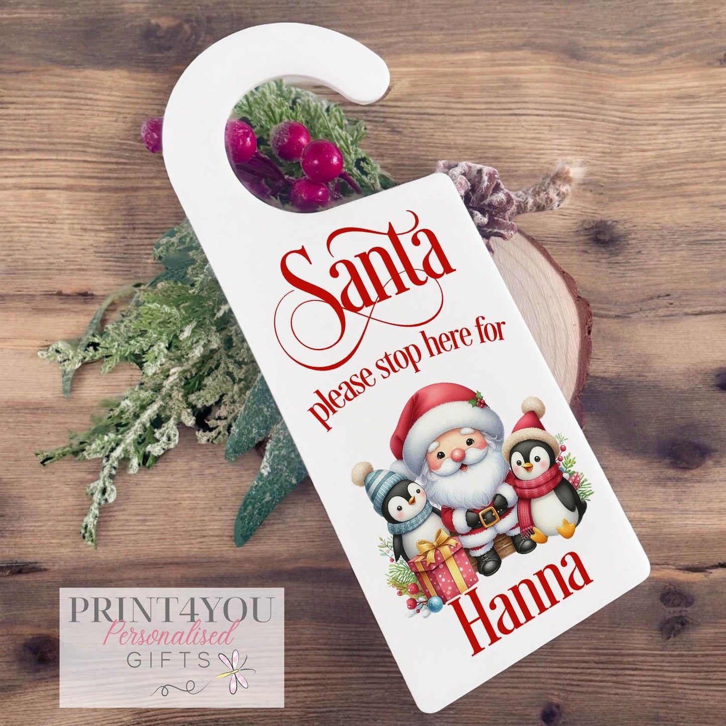 Personalised Santa Stop Here door hanger sign with custom name, festive penguin Christmas ornament design on white acrylic