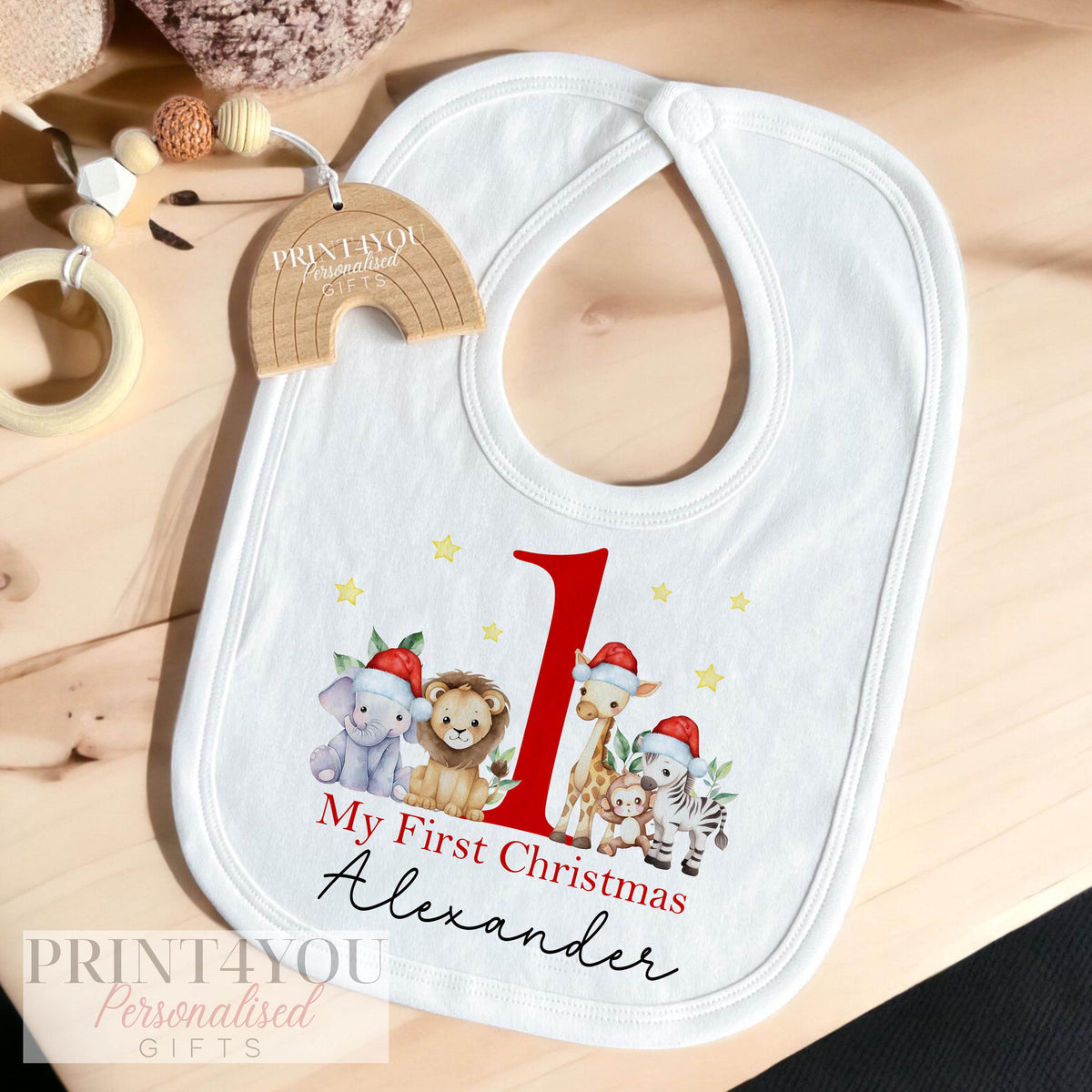 Flat lay of the Baby's First Christmas bib, vest and sleepsuit gift set, safari Santa hats print