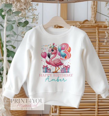 Personalised flamingo birthday design on a white cotton kids' sweatshirt, size 6-12 months.