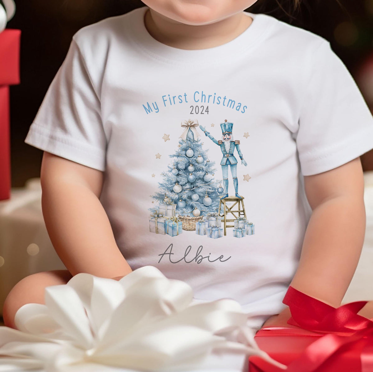 Close-up of the festive print and personalised name on a baby's first Christmas vest